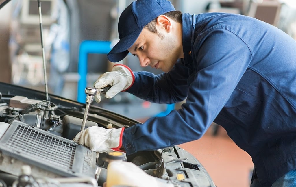 mechanic repairing kia car engine with white gloves